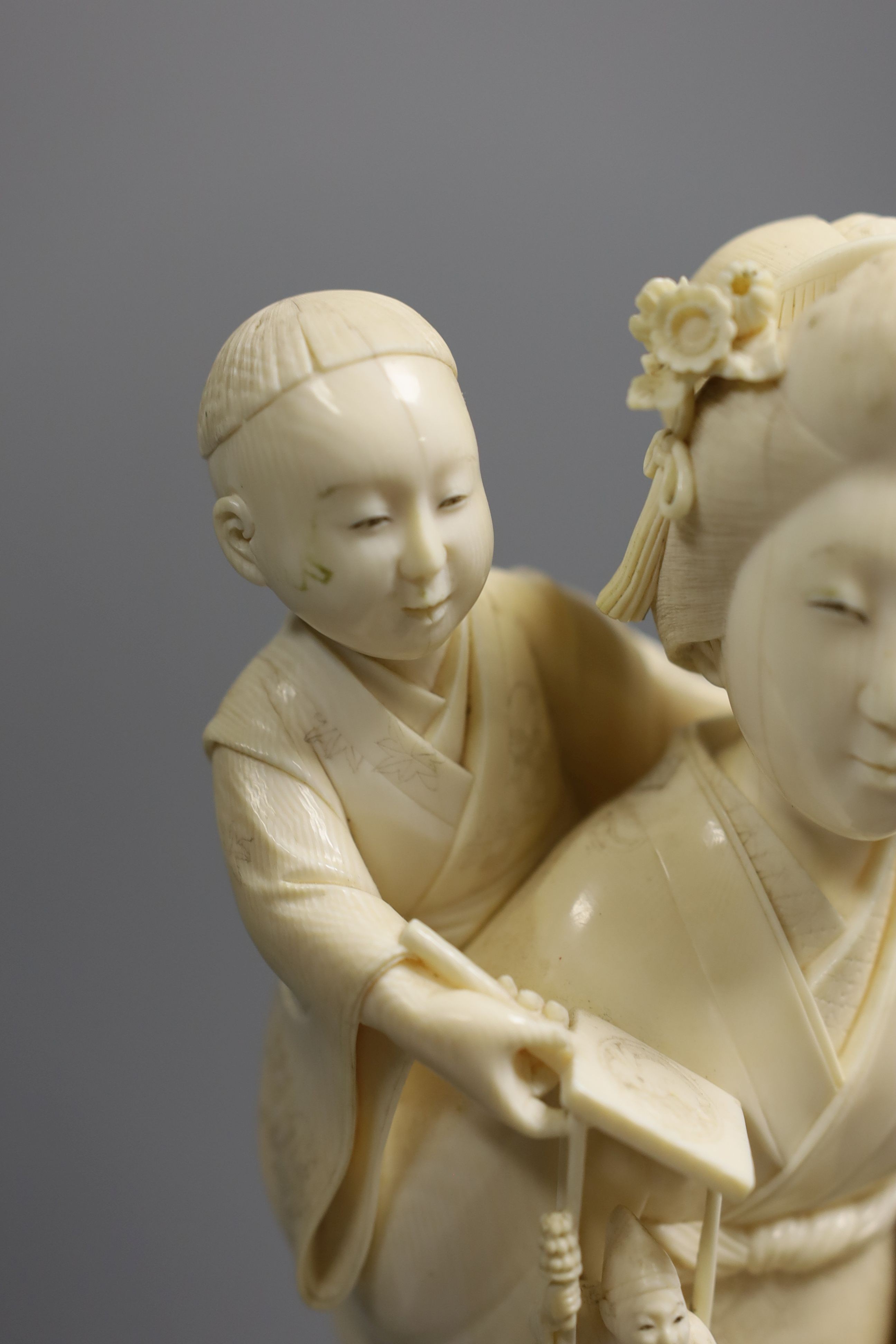 A large Japanese Tokyo School ivory okimono of a lady with child holding a puppet, Meiji period, 31 cms high.